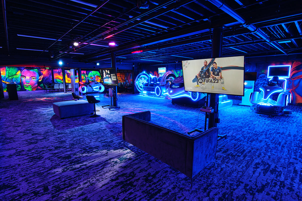GAMING PACKAGE GLENDALE in a neon lit gaming arcade with racing simulators video game stations and colorful wall art in an indoor entertainment venue