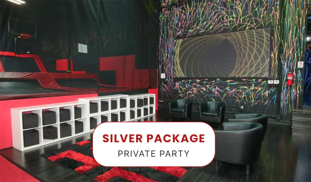 Indoor party room with black walls and colorful paint splatters, black chairs, cubby shelves, and trampoline area. Text overlay reads 